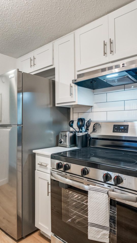 Modern kitchen featuring stainless steel appliances and white shaker cabinets.